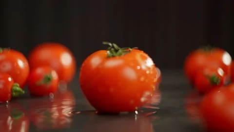 Plum tomatoes, a type of fruit, sit on a table with a black background Video stock 268282344