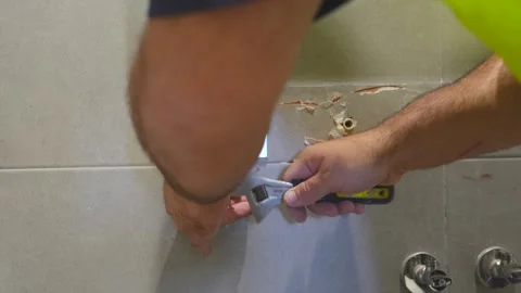 Plumber with an adjustable wrench marking where to drill holes Stock Footage 340545776