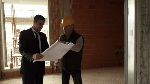 Plumber and architect talking and looking at blueprint in construction site Stock Footage