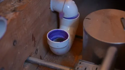 Plumber applying purple primer to a PVC pipe fitting during residential Stockbeeldmateriaal 346802203