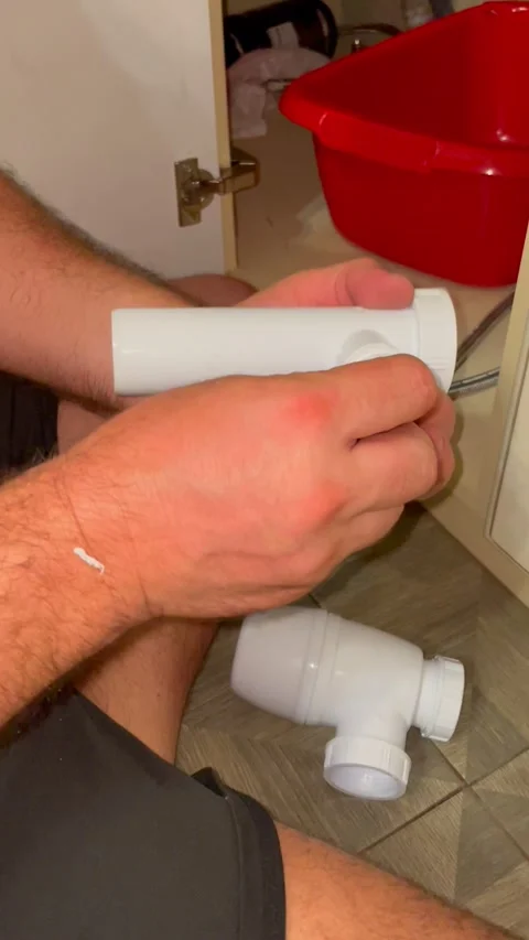 Plumber assembles white plastic sink drain pipe components. Man repairing Stock Footage 340124684