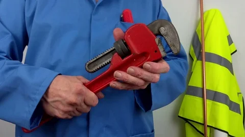 Plumber in blue overalls opening an adjustable wrench Stock Footage 79419645