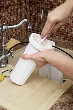 Plumber change the water filter. installing osmosis in home. male hand spins the Stock Photos