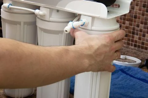 Plumber change the water filter. installing osmosis in home. male hand spins the Stock Photos