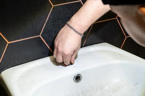 Plumber changes broken, leaking plumbing fixtures in the kitchen. Stock Photos