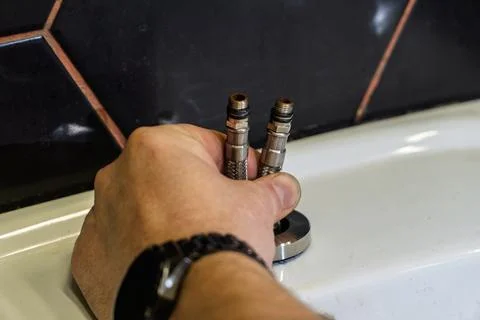 Plumber changes broken, leaking plumbing fixtures in the kitchen. Stock Photos