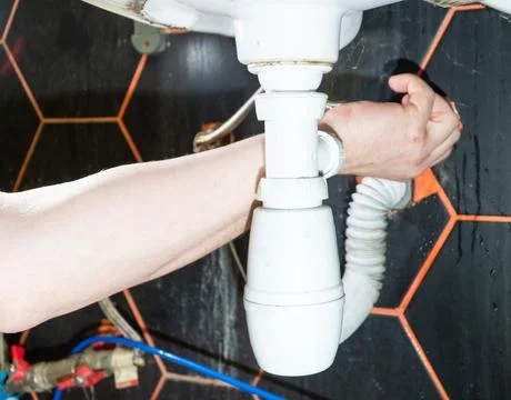 Plumber changes broken, leaking plumbing fixtures in the kitchen. Stock Photos