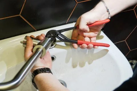 Plumber changes broken, leaking plumbing fixtures in the kitchen. Stock Photos