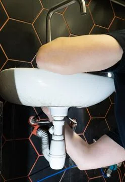 Plumber changes broken, leaking plumbing fixtures in the kitchen. Stock Photos