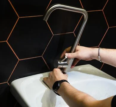 Plumber changes broken, leaking plumbing fixtures in the bathroom. Repair o.. Stock Photos