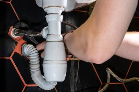 Plumber changes broken, leaking plumbing fixtures in the bathroom. Repair o.. Stock Photos