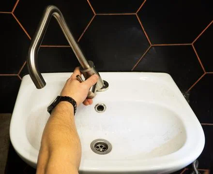 Plumber changes broken, leaking plumbing fixtures in the bathroom. Repair o.. Stock Photos