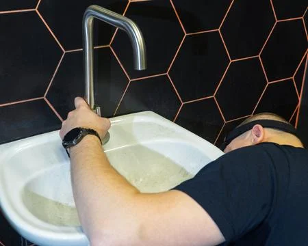 Plumber changes broken, leaking plumbing fixtures in the bathroom. Repair o.. Stock Photos