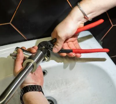 Plumber changes broken, leaking plumbing fixtures in the bathroom. Repair o.. Stock Photos