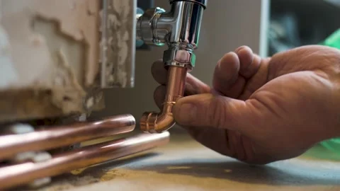 Plumber checking fitment of copper pipe work to newly fitted radiator at home Stock Footage 148955320