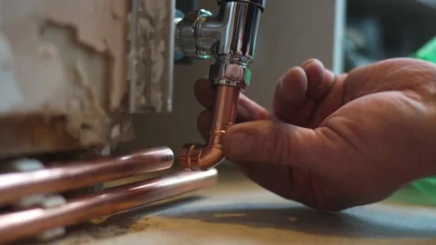 Plumber checking fitment of copper pipe work to newly fitted radiator at home Stock Footage 148998590