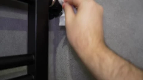 Plumber cleaning a wall mounted black heated towel rail Video stock 308940363