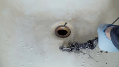 Plumber clears the blockage in the bathroom with the help of a plumbing snake Stock Footage 101483689