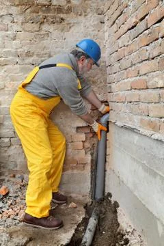 Plumber at construction site installing sewerage tube Фото