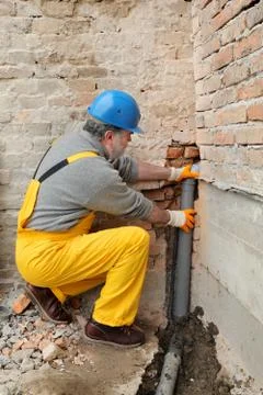 Plumber at construction site installing sewerage tube Stockfoto's