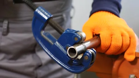 Plumber cuts a metal pipe with a pipe cutter Stock Footage 279074327