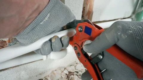 A plumber cuts a PVC pipe with a cutter. Video stock 260927128