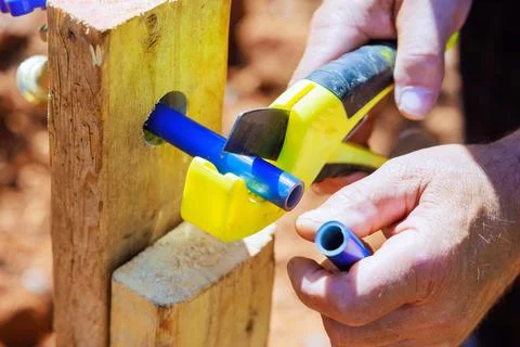 Plumber cutting blue plastic PVC water piping using saw a tool Stock Photos