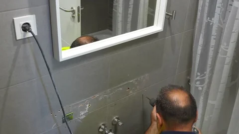 Plumber drilling a hole in a bathroom ceramic tile wall Stock Footage 340358189