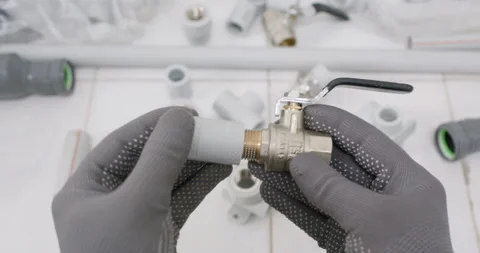 Plumber fits coupling onto brass valve and checks thread seal Stockbeeldmateriaal 322007764