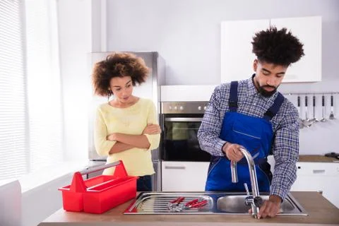 Plumber Fixing Faucet In Kitchen Stock Photos