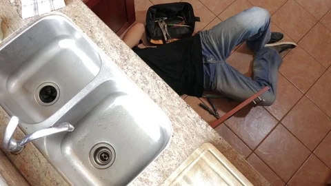 Plumber fixing the sink in a kitchen lying on the floor Stock Footage 71837278