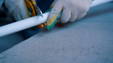 Plumber gloves cut PVC pipe with scissors. Gloved hands closeup. Stock Footage 131370179