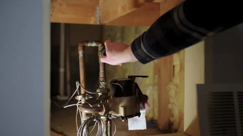 A plumber hand adjusting a valve on a copper water pipe system under a kitchen Stock Footage 303786869