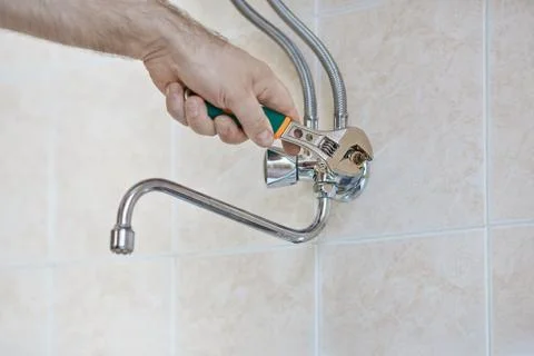 Plumber hands disassembles kitchen faucet Stock Photos