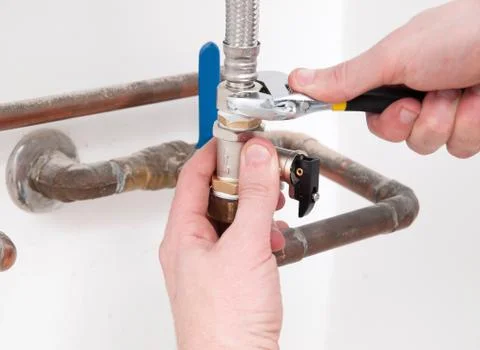 Plumber hands fixing a valve with spanner Foto stock