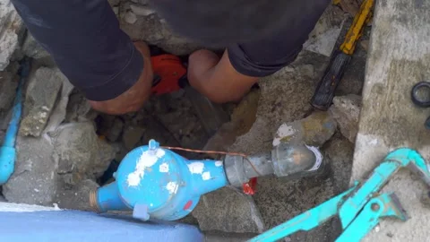 Plumber hands repairing underground pipe leak through concrete opening. Hig.. Video stock 331280501