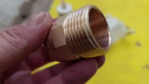 Plumber holding a new brass threaded nipple pipe fitting close up 库存影片 336562530