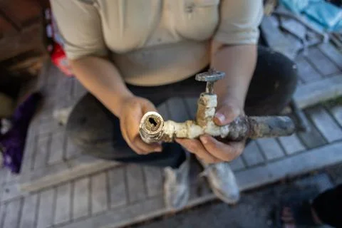 Plumber holding up a section of an old, corroded water pipe, showing the severe Stock Photos
