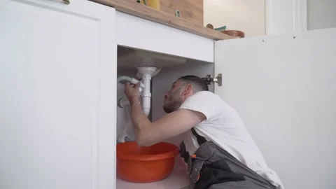 Plumber Inspecting and Fixing Damaged Pipe Under Sink Stock Footage 311501891