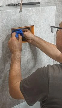 Plumber installing and adjusting a flushing mechanism inside a concealed toi 库存照片