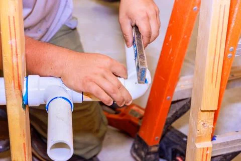 Plumber installing drainage system in a wall at new house construction Stock Photos