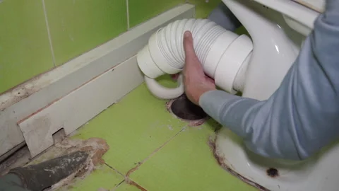 Plumber installing flexible waste pipe to toilet bowl close up Stock Footage 338405652