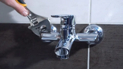 Plumber installing a mixer tap in a bathroom, he is sitting in the bathtub close Stock-Footage 101301163