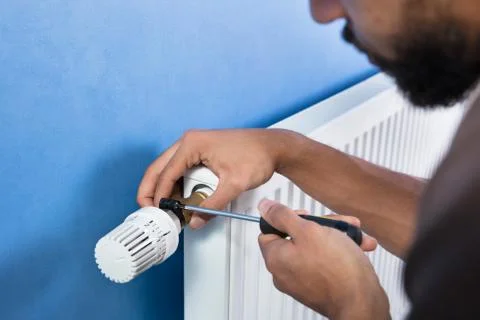 Plumber Installing Radiator With Screwdriver Foto stock