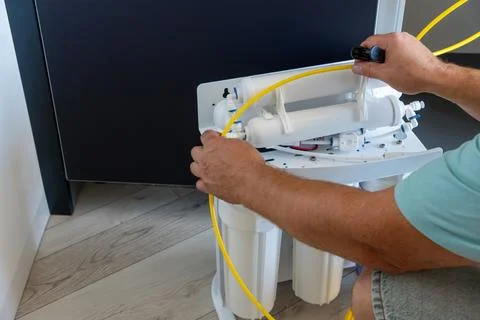 Plumber installing reverse osmosis water filter system with tube Fotos de archivo