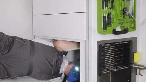 A plumber installing a sink in the kitchen room. Repair work in a new building Stock Footage 250027619