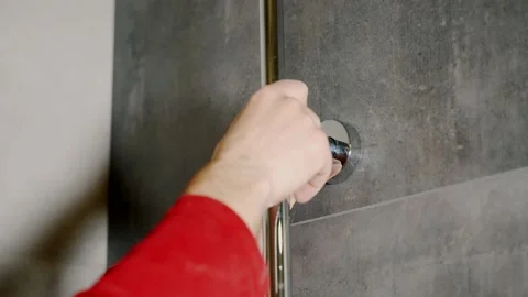 A plumber installs a chrome shower rack in the bathroom. Video stock 139744126