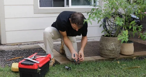 Plumber Man fixing Sprinkler Head in backyard Stock Footage 120670328