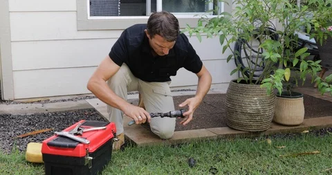 Plumber Man fixing Sprinkler Head in backyard Stock Footage 120670333