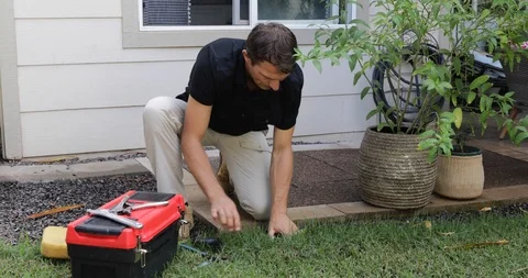 Plumber Man fixing Sprinkler Head in backyard Stock Footage 120670339